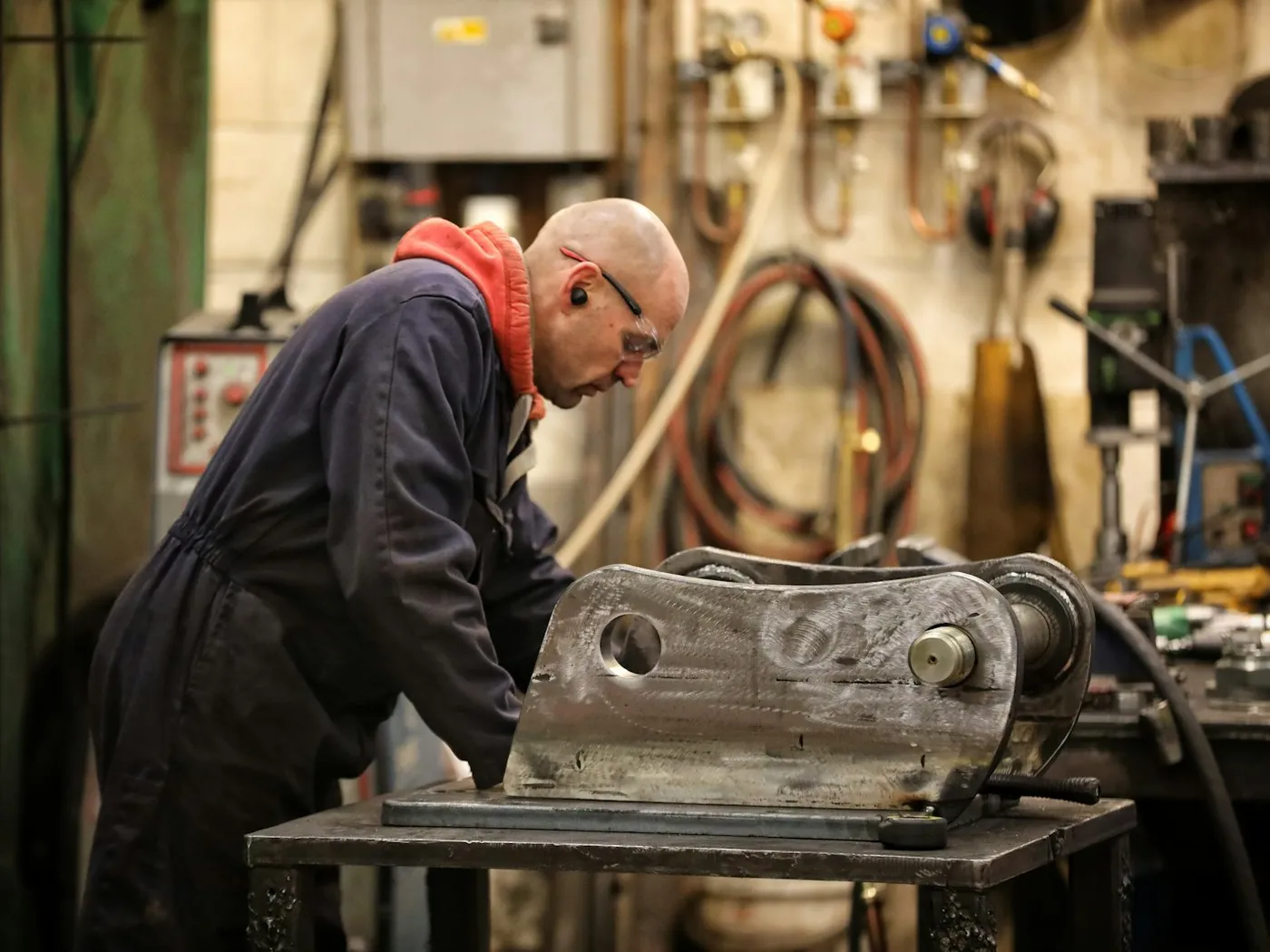 A mechanic working on a heavy machine part in a workshop