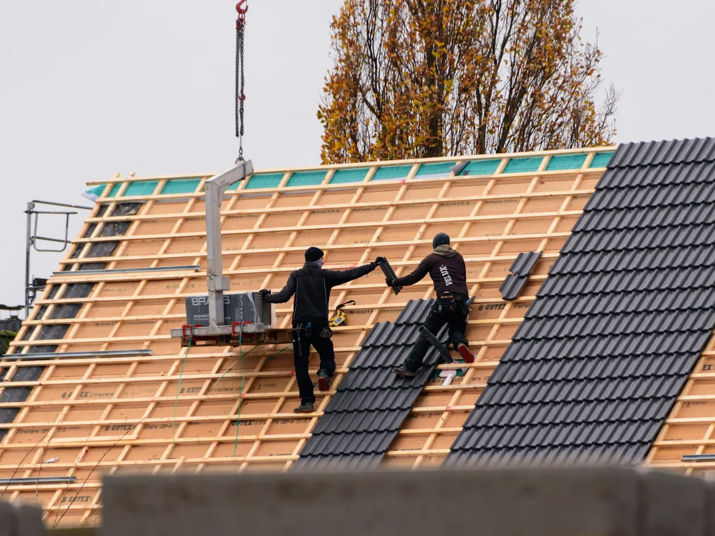 Two roofers laying tiles on a new pitched roof